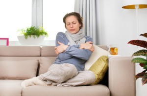 woman shivering on her couch