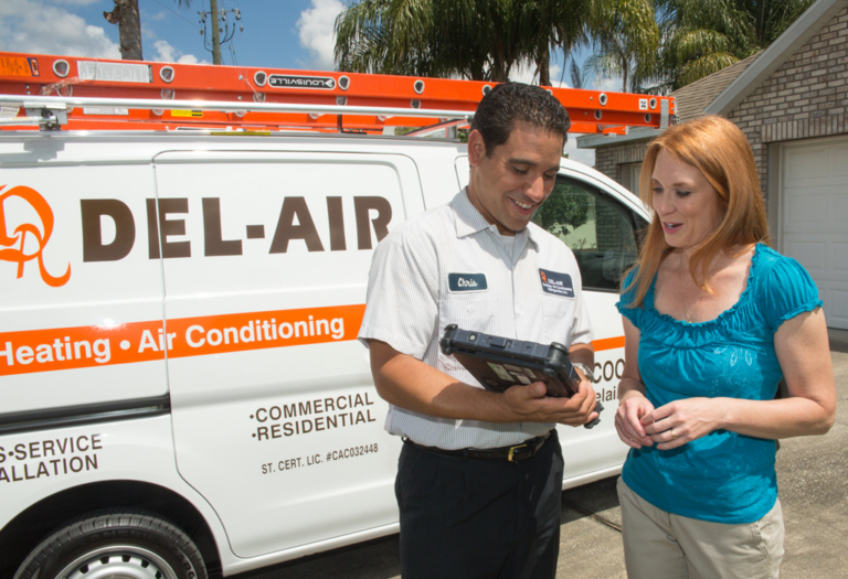 A Del-Air technician speaking with a client outside, with a service van in the background