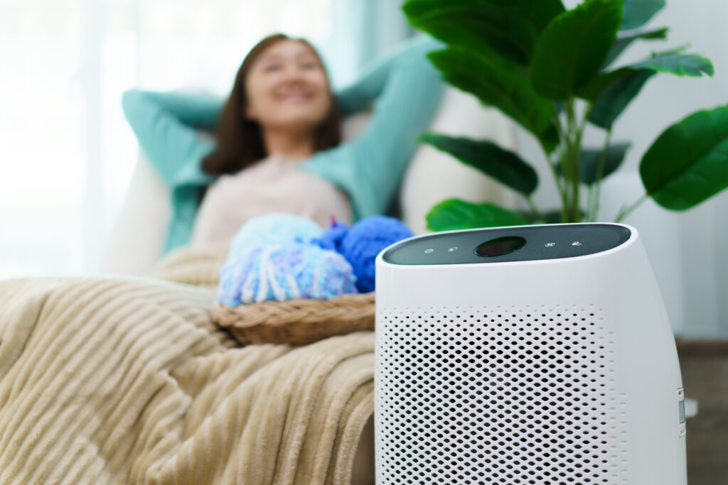 Happy person using an air purifier in their living room while relaxing in a chair
