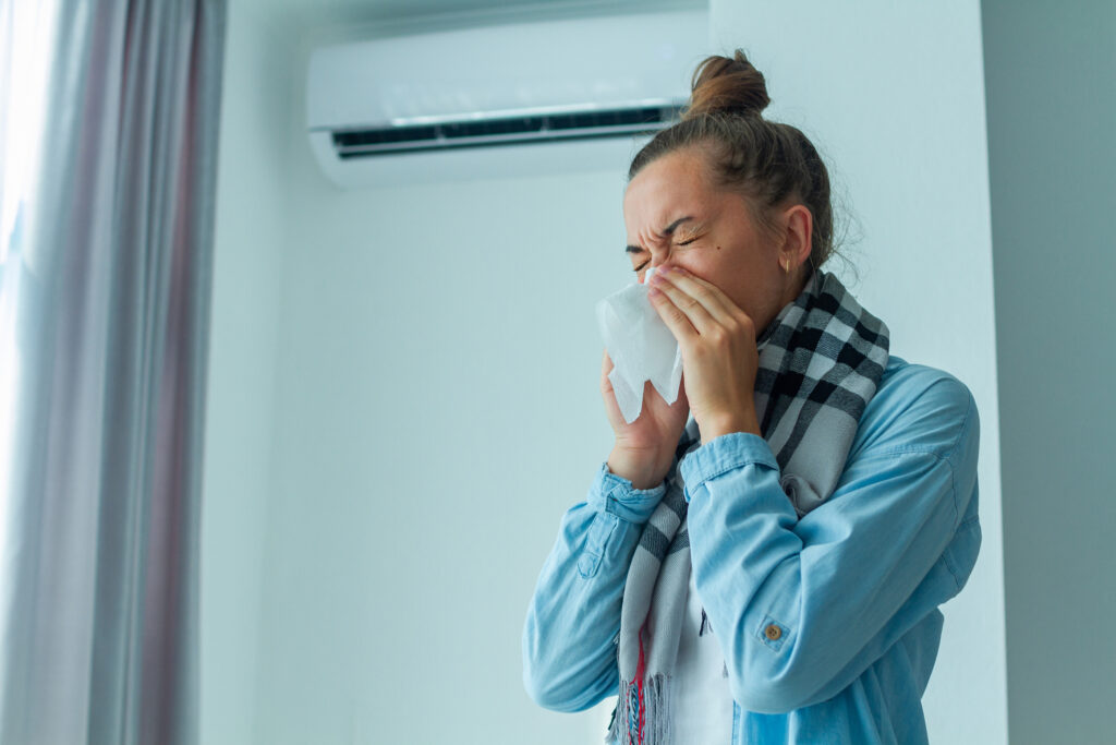A woman sneezing into a tissue due to poor indoor air quality