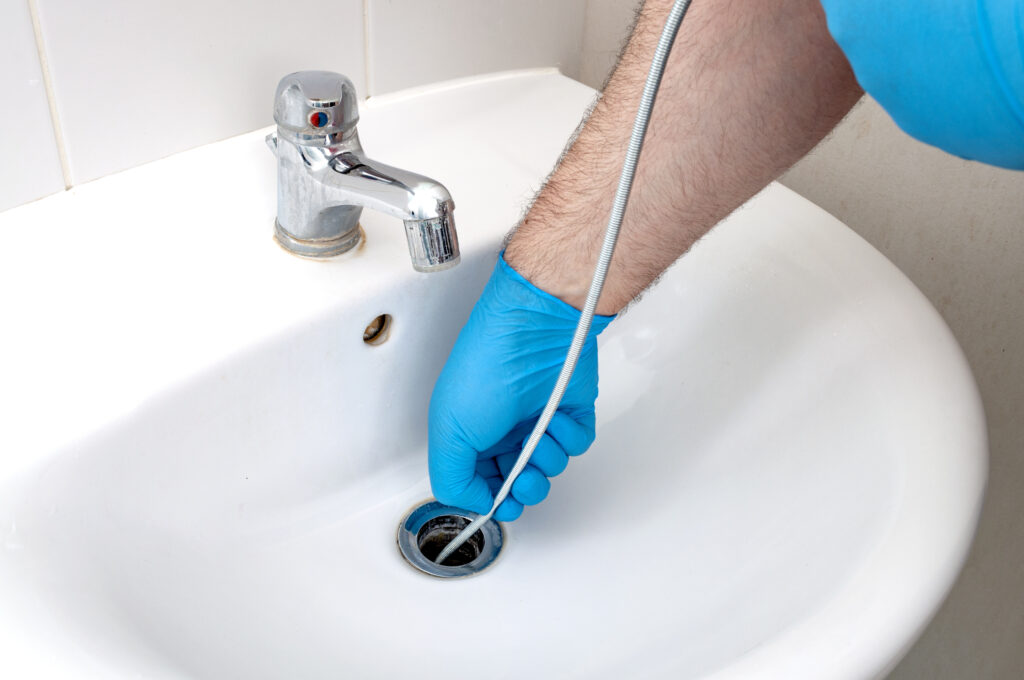 Plumber using auger to clear sink drain