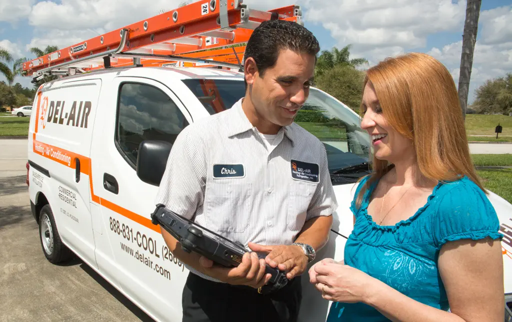 Del-Air technician speaking with a homeowner, showing her information on a tablet