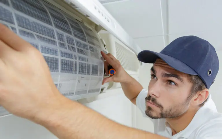 Man looking at and placing a new air filter on an air conditioning unit.