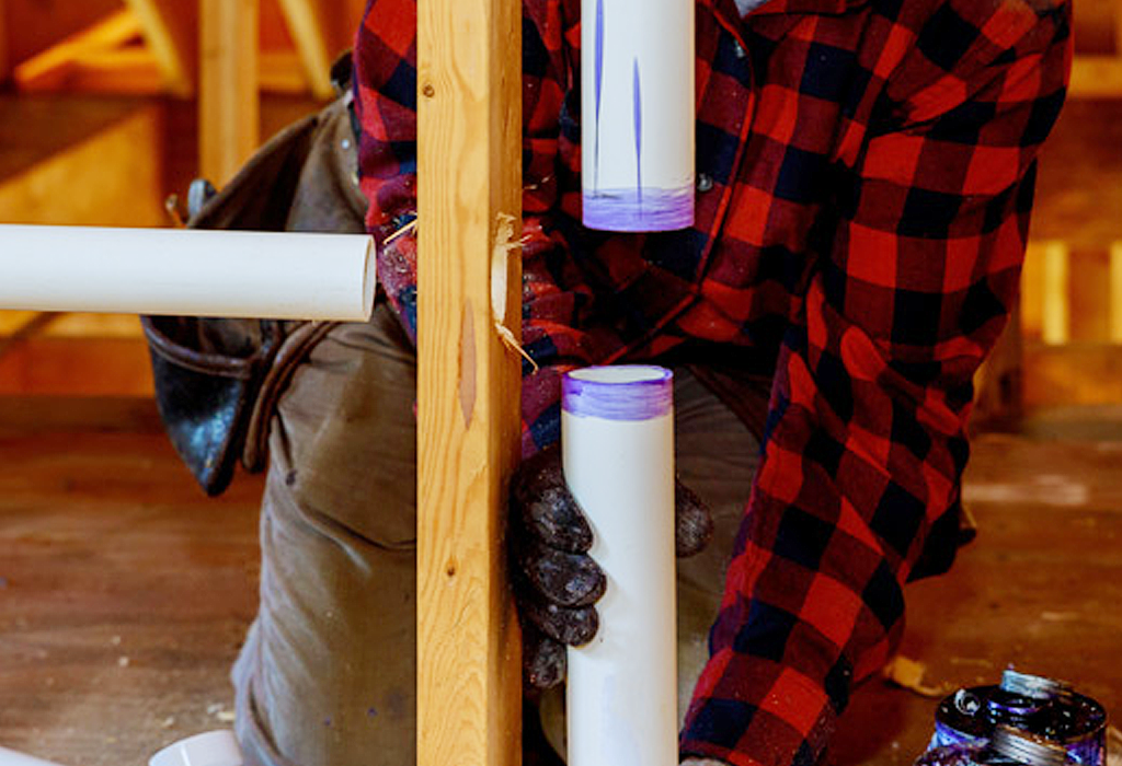 A technician installing plumbing pipes during a new construction project