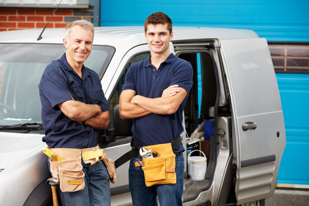 Technicians smiling outside a service van