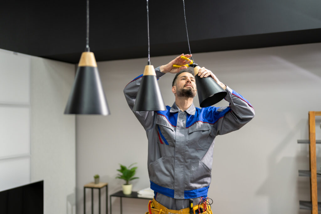 An electrician installing black pendant lights
