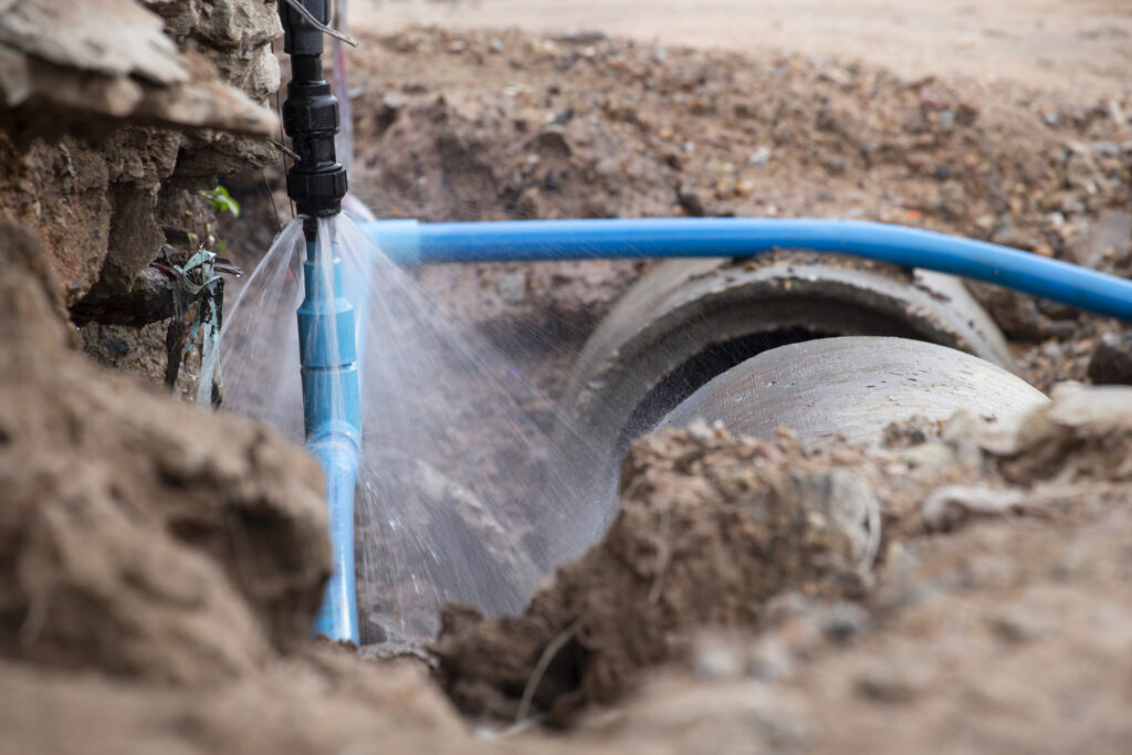 A burst water main, focused on the spraying water and the pipe.