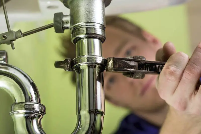 plumber using wrench on pipe